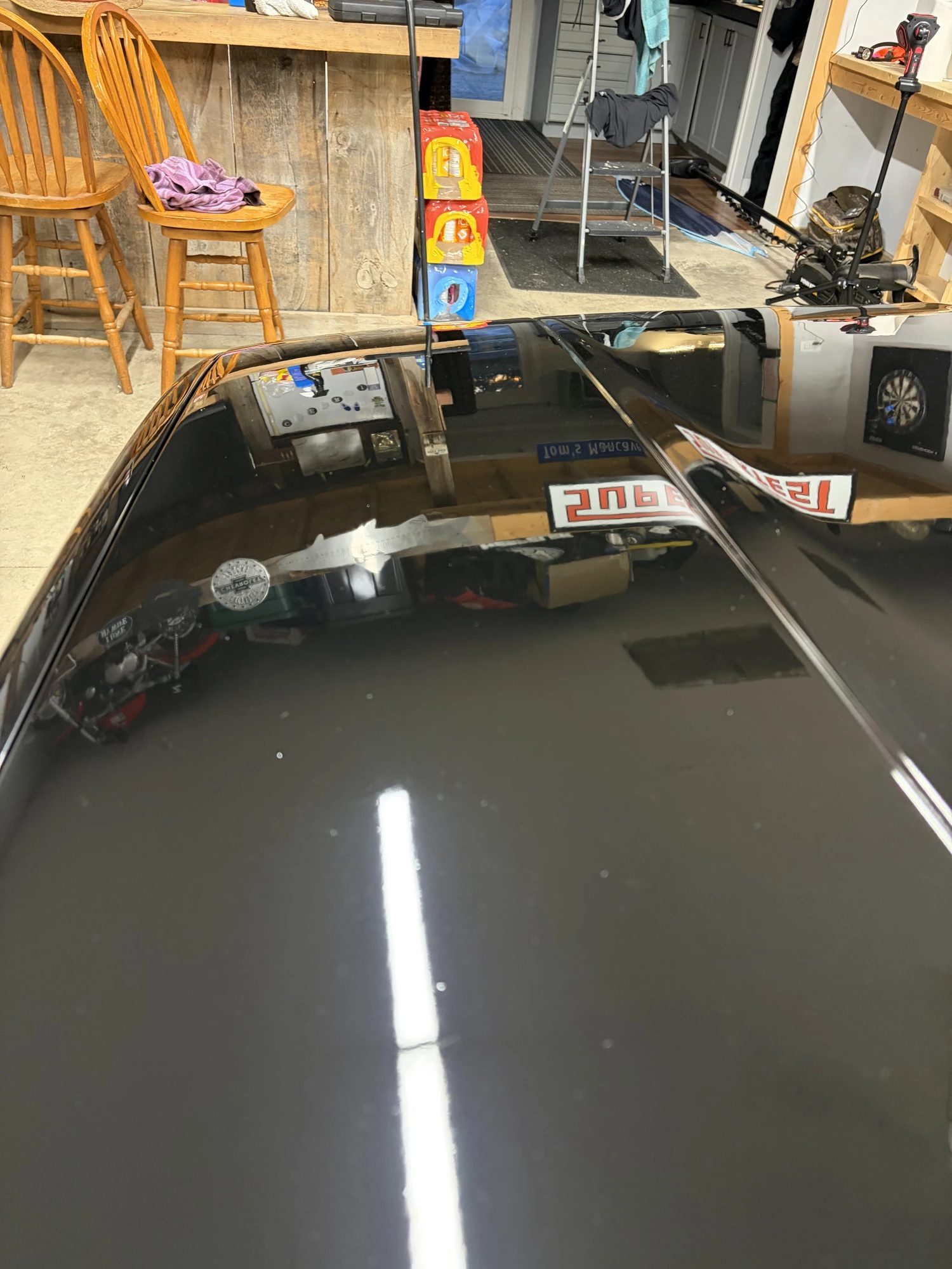 Black car paint before and after paint correction by Unreal Auto Spa — heavy swirl marks versus a corrected, glossy finish